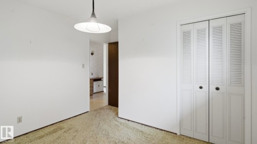 Room featuring light-toned carpeting, white painted walls, and a contemporary pendant light fixture - 7408 40 Avenue, Edmonton, AB 