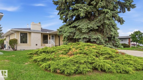 Exterior featuring pale yellow siding, white brick accents, and a dark roof - 7408 40 Avenue, Edmonton, AB 