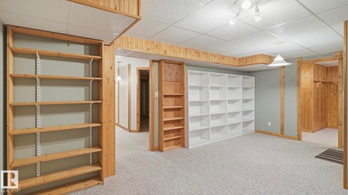 Spacious room featuring light-colored carpeting, multiple built-in shelving units, recessed lighting, and a drop ceiling - 7408 40 Avenue, Edmonton, AB 