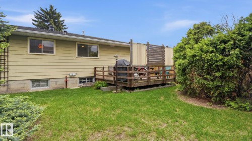 Rear exterior featuring a wood deck, mature landscaping, and a manicured lawn - 7408 40 Avenue, Edmonton, AB 