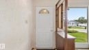 Entryway featuring a white paneled door with an arched transom window, a built-in wood-finish room divider with shelving, and large windows revealing an exterior landscape - 7408 40 Avenue, Edmonton, AB 
