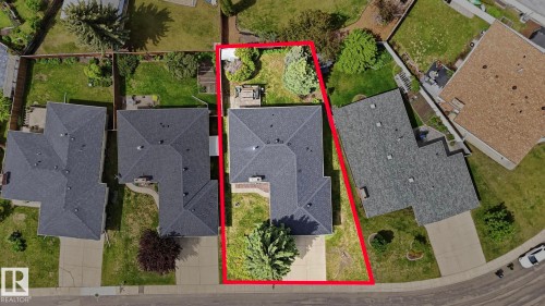 Property featuring a dark shingle roof, a concrete driveway, and a partially fenced backyard with mature trees - 7408 40 Avenue, Edmonton, AB 