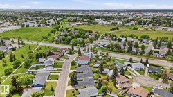 Residential neighborhood with detached homes, mature trees, and expansive green spaces - 