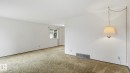 White painted walls, neutral carpeting, and a window with white trim - 7408 40 Avenue, Edmonton, AB 