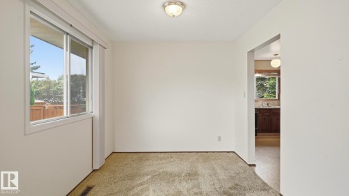 Carpeted room with a white ceiling and walls, featuring a window with white trim and an overhead flush-mount light fixture - 7408 40 Avenue, Edmonton, AB 