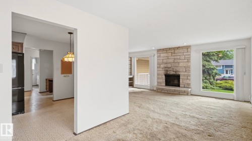 Living area featuring a stone-faced fireplace with a hearth, large windows, and recessed lighting - 7408 40 Avenue, Edmonton, AB 