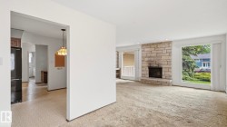 Living area featuring a stone-faced fireplace with a hearth, large windows, and recessed lighting - 