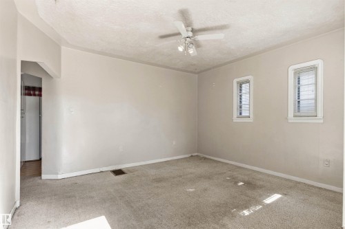 Spacious room featuring neutral painted walls, light-colored carpeting, and a ceiling fan with integrated lighting - 11417 65 Street, Edmonton, AB 