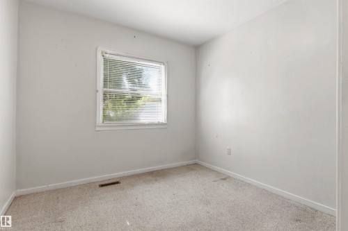 Light-filled room featuring a single window with blinds, neutral wall paint, and wall-to-wall carpeting - 11417 65 Street, Edmonton, AB 