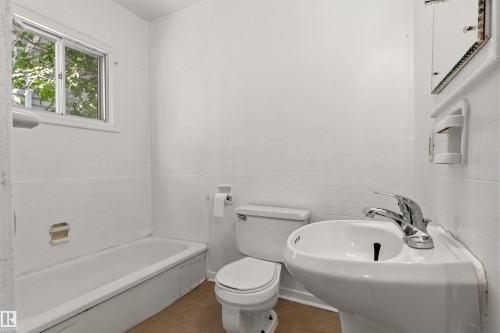 Pedestal sink with chrome faucet, white toilet, and tub with shower fixture - 11417 65 Street, Edmonton, AB 