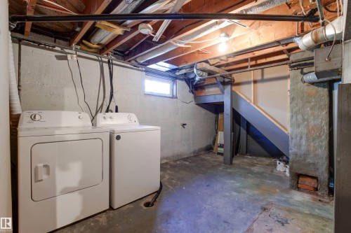 Basement utility space featuring a washer and dryer, exposed ceiling joists, concrete flooring, and a basement window - 11417 65 Street, Edmonton, AB 