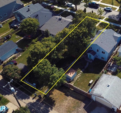 Aerial perspective of a sizable lot highlighted by a yellow boundary, featuring mature trees and a grassy area - 11417 65 Street, Edmonton, AB 