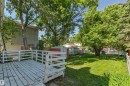 Expansive backyard featuring a white wood deck, manicured lawn, and mature trees - 11417 65 Street, Edmonton, AB 