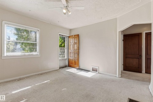 Spacious room with light-colored carpeting, a multi-pane window with white blinds, and a paneled wood door - 11417 65 Street, Edmonton, AB 