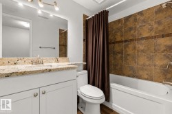 Full bathroom featuring a white vanity with a granite countertop, a built-in sink, and brushed nickel fixtures - 
