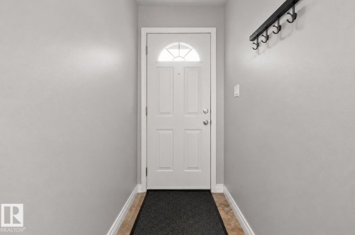 Entryway featuring a white paneled door with an arched glass insert, light gray walls, and light-toned tile flooring - 11234 40 Avenue, Edmonton, AB 