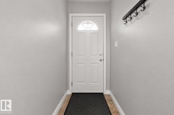 Entryway featuring a white paneled door with an arched glass insert, light gray walls, and light-toned tile flooring - 