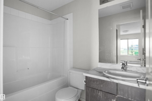 Bathroom featuring a white bathtub, toilet, and a vanity with a white countertop - 202 142 Ebbers Boulevard, Edmonton, AB 