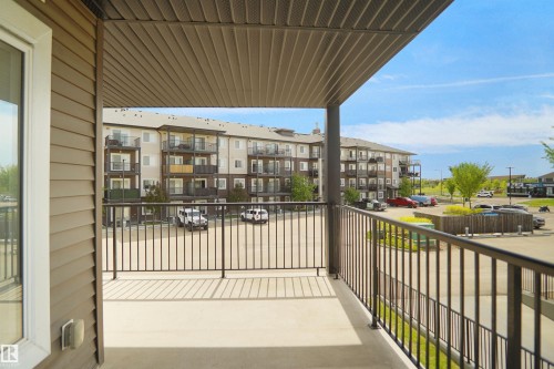 Covered balcony with concrete flooring and dark metal railings - 202 142 Ebbers Boulevard, Edmonton, AB 