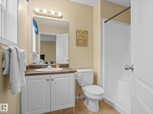 Bathroom featuring a white vanity with a brown countertop, an integrated sink, and white cabinetry - #88 5001 62 St, Beaumont, AB - Indoor Photo Showing Bathroom
