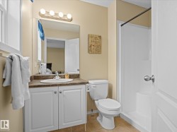 Bathroom featuring a white vanity with a brown countertop, an integrated sink, and white cabinetry - 