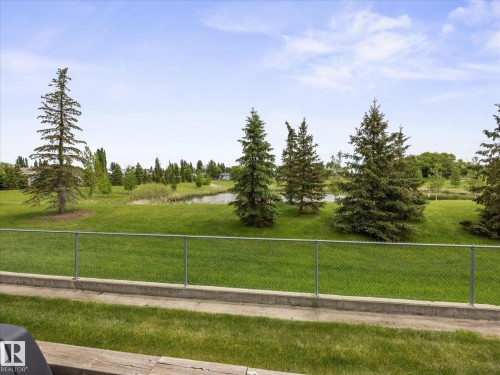 Expansive green space featuring mature evergreen trees and a visible pond - #88 5001 62 St, Beaumont, AB - Outdoor With View