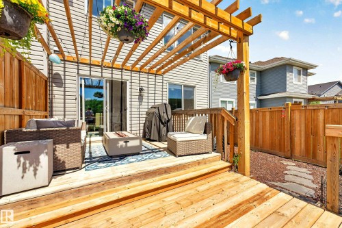 Expansive wood deck featuring a pergola, sliding glass door access, horizontal siding, wood privacy fencing, and stepping stone pathway - 20507 128 Avenue, Edmonton, AB 