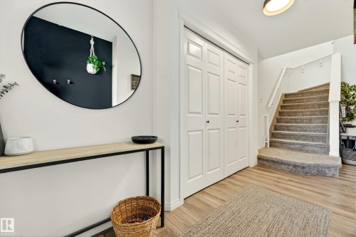 Entryway featuring wood-finish flooring, white bifold closet doors, and carpeted stairs with white railing - 20507 128 Avenue, Edmonton, AB 
