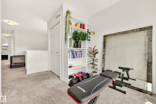 Carpeted room featuring a built-in white bookshelf, bi-fold closet doors, and a decorative wall mirror - 20507 128 Avenue, Edmonton, AB 