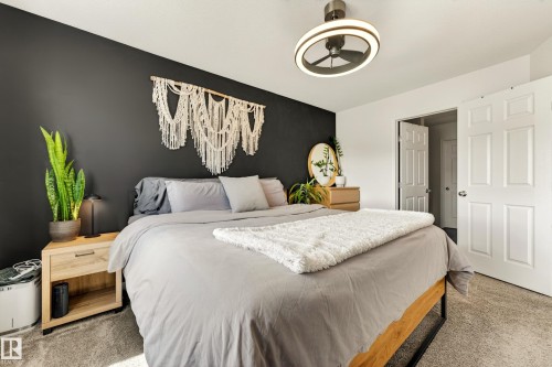 Bedroom featuring a dark accent wall, light-colored carpeting, and a modern ceiling fan with integrated lighting - 20507 128 Avenue, Edmonton, AB 