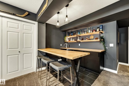 Dedicated bar area featuring a wood-finish countertop, black cabinetry, and industrial-style open shelving - 20507 128 Avenue, Edmonton, AB 