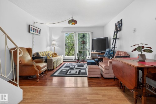 Living area featuring wood-finish flooring, white walls, and a sliding glass door to an exterior space - 204 12404 114 Avenue, Edmonton, AB - Indoor Photo Showing Living Room