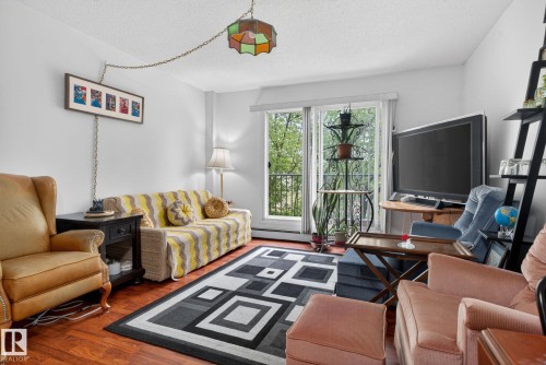 Spacious living area featuring rich wood-finish flooring and ample natural light from the sliding glass door - 204 12404 114 Avenue, Edmonton, AB - Indoor Photo Showing Living Room