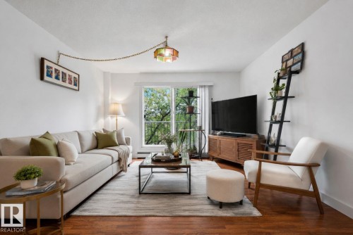 Bright living space with wood-finish flooring, white walls, and a glass-paneled sliding door opening to a balcony - 204 12404 114 Avenue, Edmonton, AB - Indoor Photo Showing Living Room