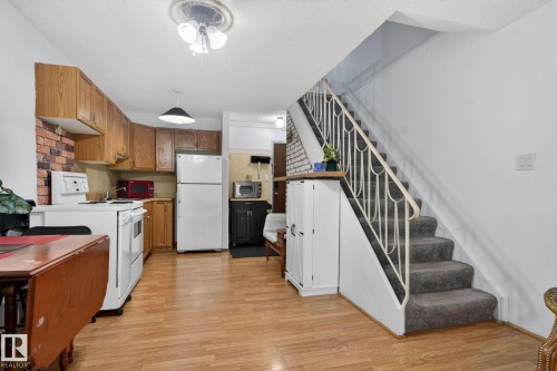 Kitchen area featuring wood-finish flooring, light wood cabinetry, and a brick-patterned backsplash - 204 12404 114 Avenue, Edmonton, AB - Indoor Photo Showing Kitchen