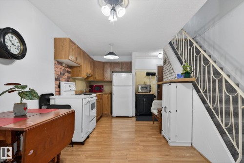 Kitchen area featuring wood-finish flooring, wood cabinetry, and a brick-patterned backsplash - 204 12404 114 Avenue, Edmonton, AB - Indoor Photo Showing Kitchen