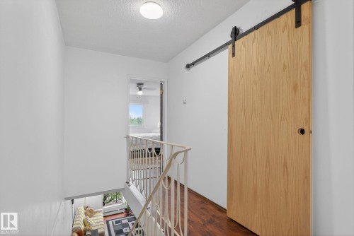 Modern barn door with a wood-finish panel and black hardware - 204 12404 114 Avenue, Edmonton, AB - Indoor Photo Showing Other Room
