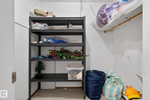 Storage closet featuring a freestanding black metal shelving unit, white walls, and a built-in upper shelf with a hanging rod - 204 12404 114 Avenue, Edmonton, AB - Indoor