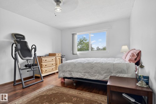 Bedroom featuring wood-finish flooring, white walls, and a window with exterior greenery - 204 12404 114 Avenue, Edmonton, AB - Indoor Photo Showing Bedroom