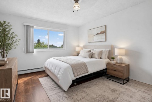 Hardwood-style flooring throughout, complemented by a large window with vertical blinds - 204 12404 114 Avenue, Edmonton, AB - Indoor Photo Showing Bedroom