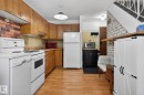 Functional kitchen featuring wood-finish flooring, light wood cabinetry, white appliances, and a brick-patterned backsplash - 204 12404 114 Avenue, Edmonton, AB  - Indoor Photo Showing Kitchen 
