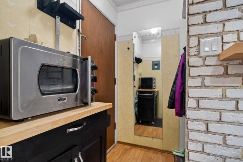 Distressed white brick wall with a light wood floating shelf - 204 12404 114 Avenue, Edmonton, AB - Indoor Photo Showing Other Room