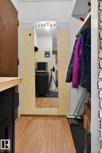 Hallway featuring wood-finish flooring, a full-length wall mirror, and a built-in storage shelf - 204 12404 114 Avenue, Edmonton, AB - Indoor