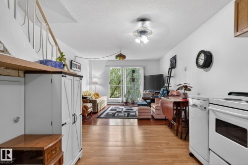 Open-concept living area featuring wood-finish flooring, a ceiling fan, and sliding glass doors leading to an exterior space - 204 12404 114 Avenue, Edmonton, AB - Indoor