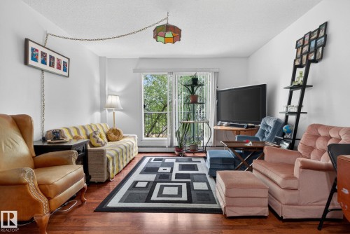 Living area featuring wood-finish flooring, a glass sliding door, and white walls - 204 12404 114 Avenue, Edmonton, AB - Indoor Photo Showing Living Room
