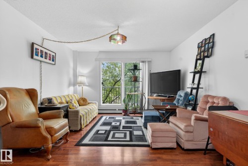 Living area featuring wood-finish flooring, white walls, and a balcony with an iron railing - 204 12404 114 Avenue, Edmonton, AB - Indoor Photo Showing Living Room