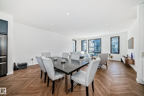 Open-concept living area featuring chevron wood-finish flooring, recessed lighting, and large windows with black frames - 46 1304 Rutherford Road, Edmonton, AB - Indoor Photo Showing Dining Room