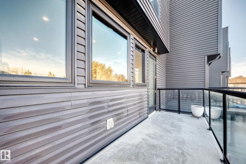 Outdoor balcony featuring a concrete surface, glass railing with black framing, and a glass-paneled door - 46 1304 Rutherford Road, Edmonton, AB - Outdoor