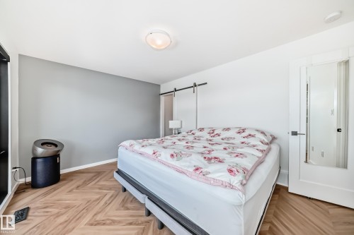 Bedroom featuring wood-finish flooring in a herringbone pattern, a light gray accent wall, and a white ceiling with a flush-mount light fixture - 46 1304 Rutherford Road, Edmonton, AB - Indoor Photo Showing Bedroom