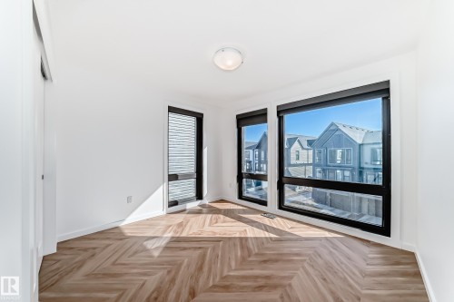 Bright room with wood-finish flooring in a chevron pattern - 46 1304 Rutherford Road, Edmonton, AB - Indoor Photo Showing Other Room
